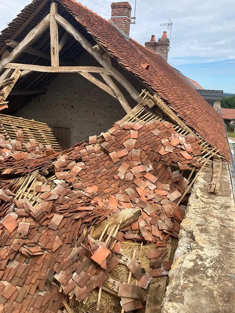 Toiture effondrée d’un bâtiment ancien avec tuiles plates en terre cuite