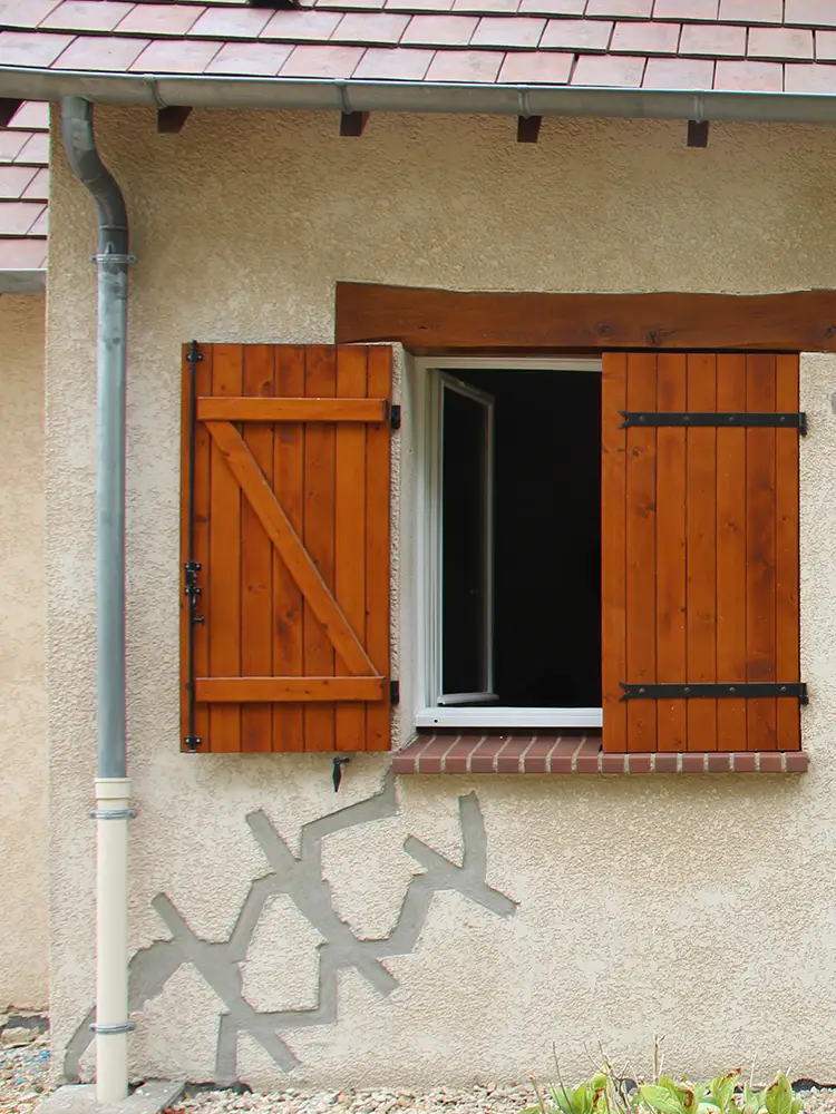 Façade d'une maison avec reprises de fissures en escalier sous une fenêtre