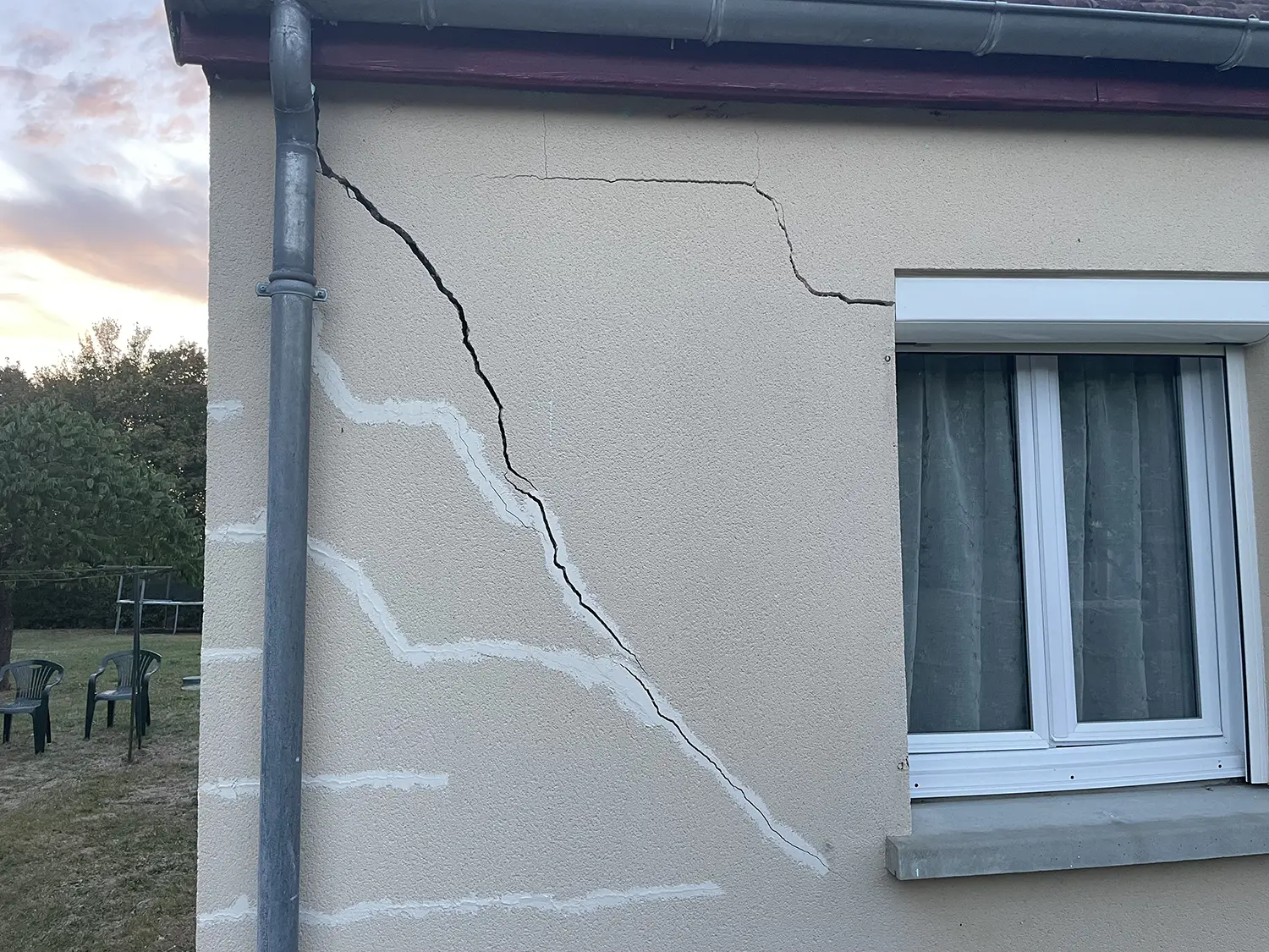 Fissure en escalier importante sur façade d’une maison entre une fenêtre et un angle de mur.
