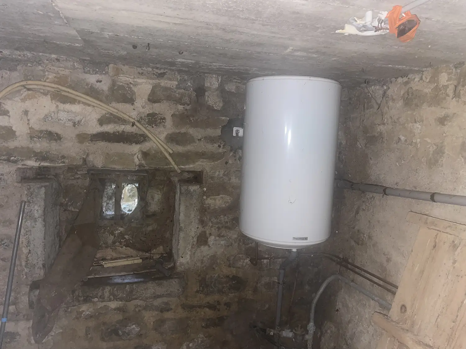 Ballon d’eau chaude dans une cave en pierre avec ventilation rudimentaire