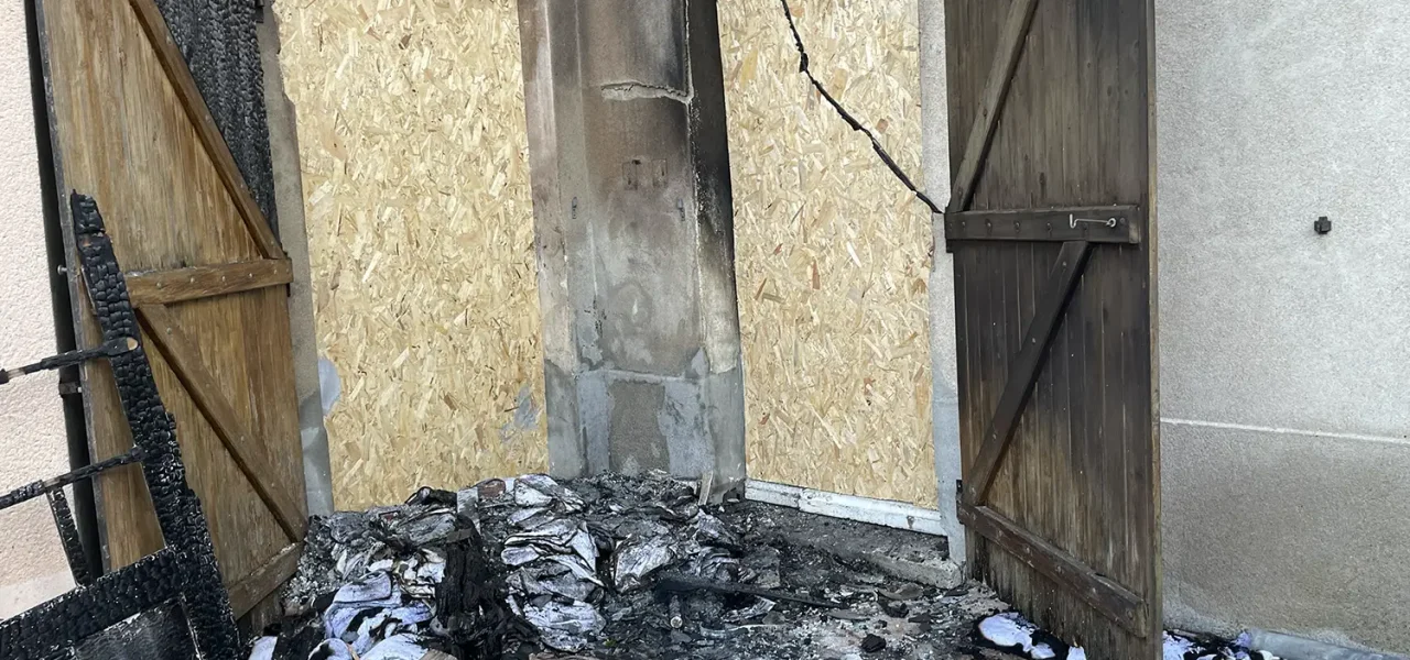 Façade extérieure d'une maison incendiée avec volets brûlés et ouvertures condamnées