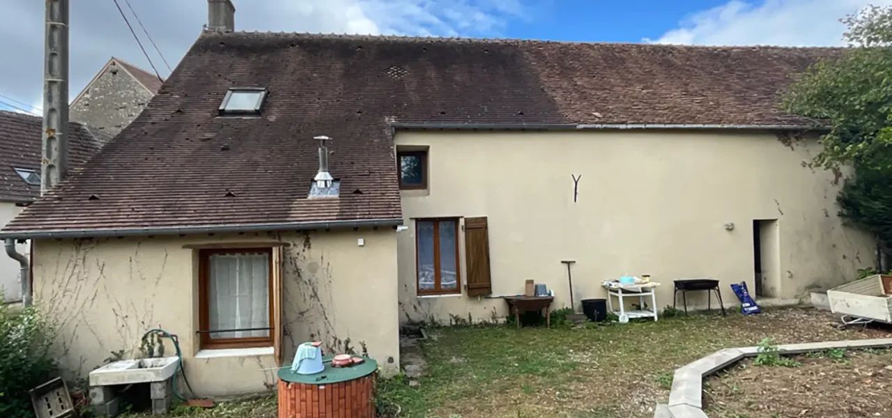 Maison ancienne avec façade beige, toit en tuiles et jardin en cours d'aménagement